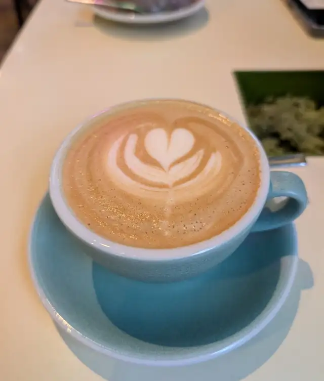 Latte z wzorem serca w niebieskiej filiżance